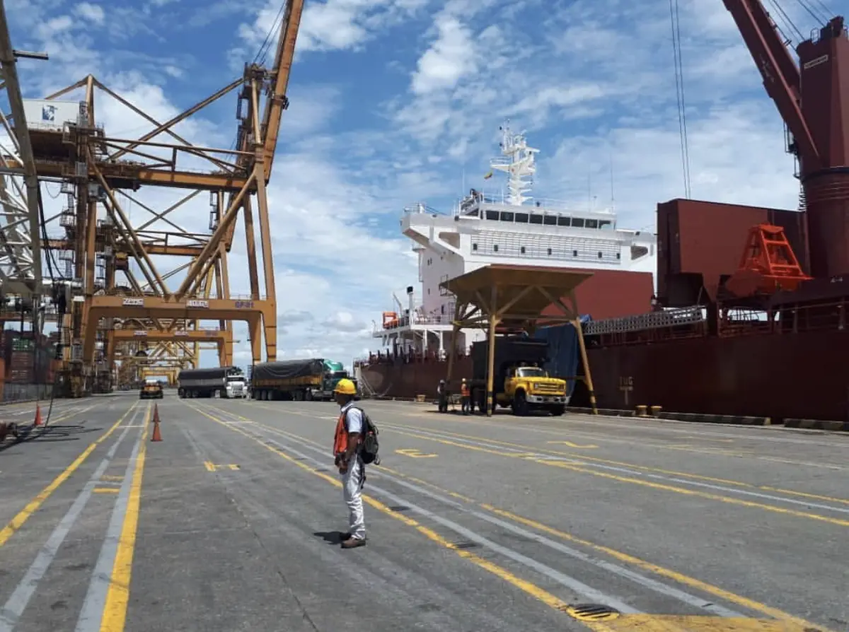 Muelle portuario con grúas pórtico y un buque de carga atracado.
